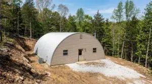 Quonset metal garage in a forested area in Quebec, showcasing durable steel construction.