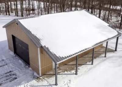 Aerial view of a snow-covered steel maintenance shop in a rural area.