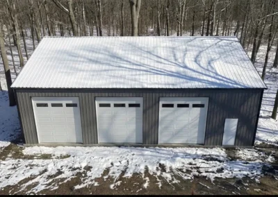 Aerial view of insulated 30x50 steel workshop with three doors in snowy forest setting