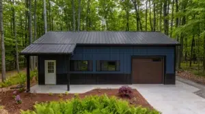 Navy blue metal garage with workshop in a wooded lot