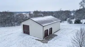 White steel garage with brown roof in snowy landscape