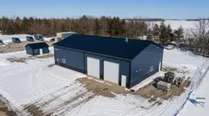 Navy blue metal garage workshop in snowy landscape, aerial view.