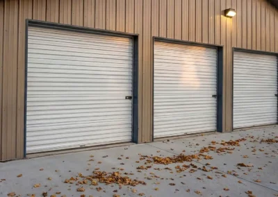 Multi-unit steel business plaza with closed garage doors and driveway.